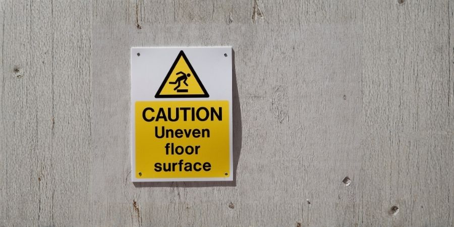 How to Tell Whether Uneven Floors Indicate Foundation Movement Caution sign warning of uneven floor surface at Pinnacle Structural Repairs.